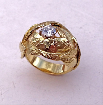 Yellow gold ring with sculpted leaves surrounding a round diamond.