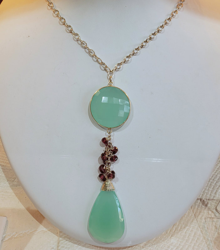Sterling Silver necklace with a faceted round and pear shaped Aqua Chalcedony with small Rhodolite Garnet dangling beads between them.