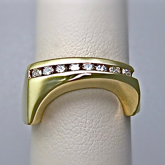 18 Karat Yellow Gold ring with channel set diamonds across the top and angled down sections on gold on each side.