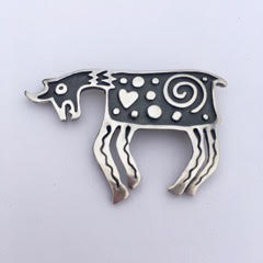 Sterling Silver pin in the shape of a goat with a spiral and heart and dotted pattern with oxidized background.
