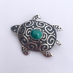 Sterling Silver turtle shaped pin with a bezel set Turquoise, spiral designs and oxidation in the background.
