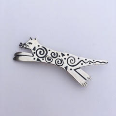 Sterling Silver jumping cat pin with spiral designs.