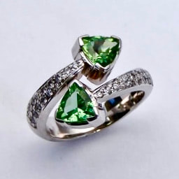 14 Karat White Gold bypass ring with two trillion shaped Green Tourmalines and diamonds down each side.