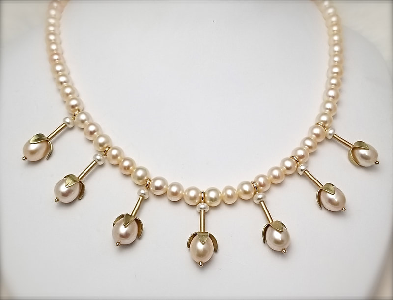 14 Karat Yellow Gold and 14 Karat Green Gold Pearl strand with 7 stations of one pearl with petal caps spaced around the bottom of the necklace.