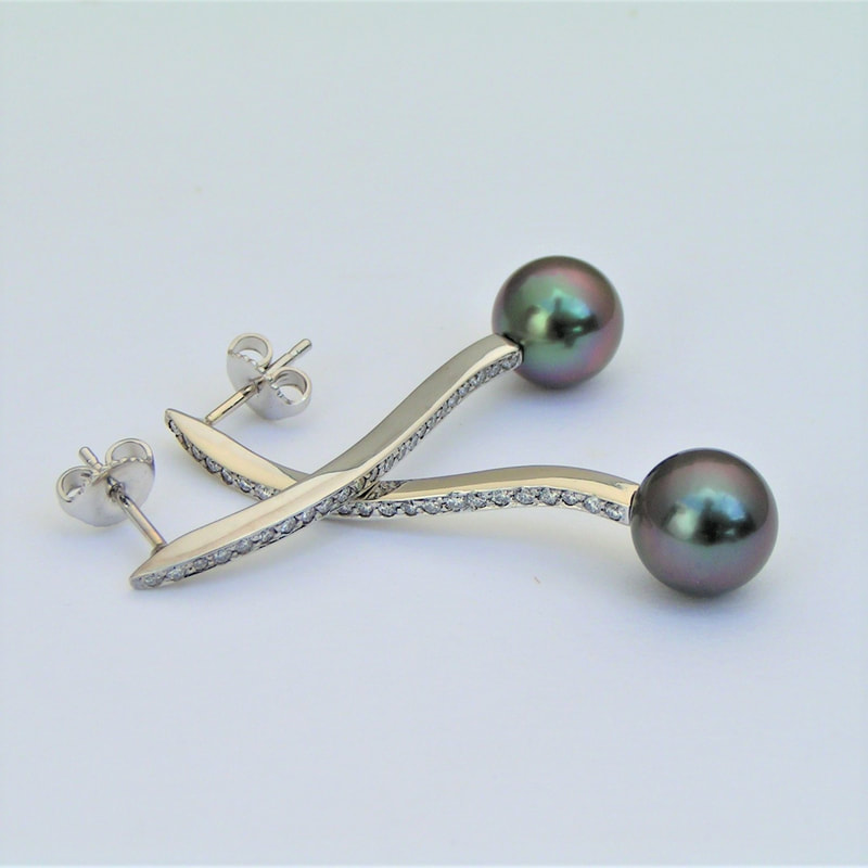 14 Karat White Gold post earrings with a Tahitian Black Pearl at the bottom of a line of diamonds.