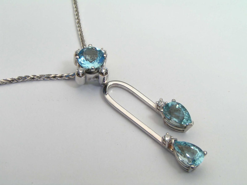 14 Karat White Gold pendant with a round Aquamarine with an attached station with two pear shaped Aquamarines at the bottom.