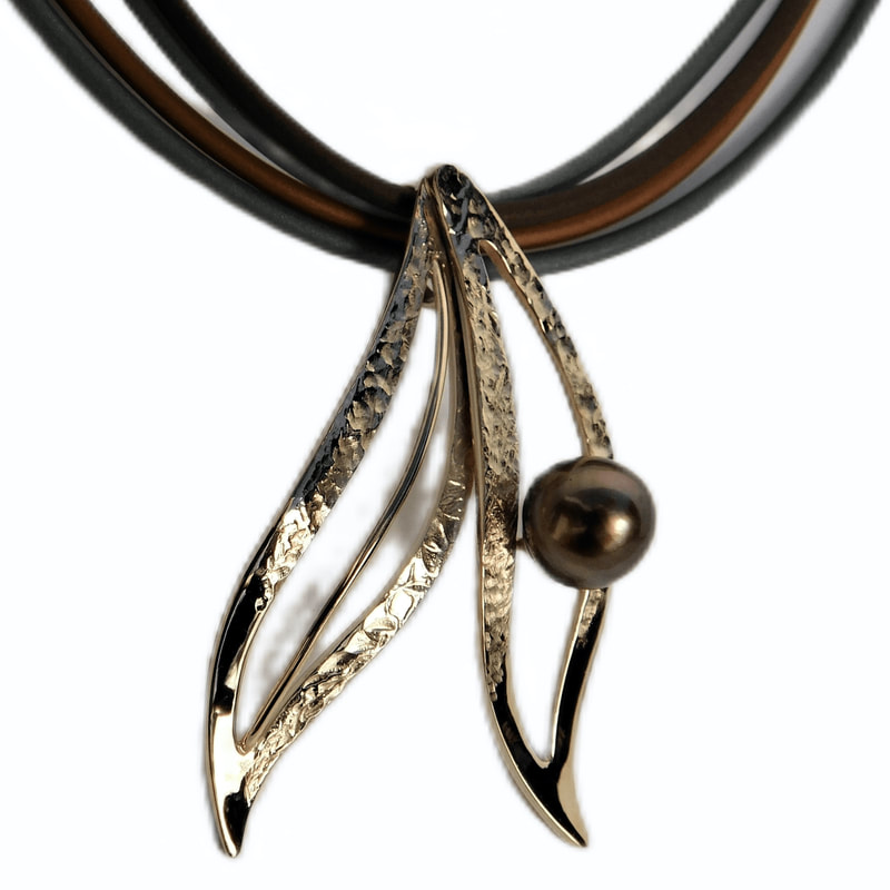14 Karat Yellow Gold double open leaf pendant with a Tahitian pearl on 3 strands of neoprene.