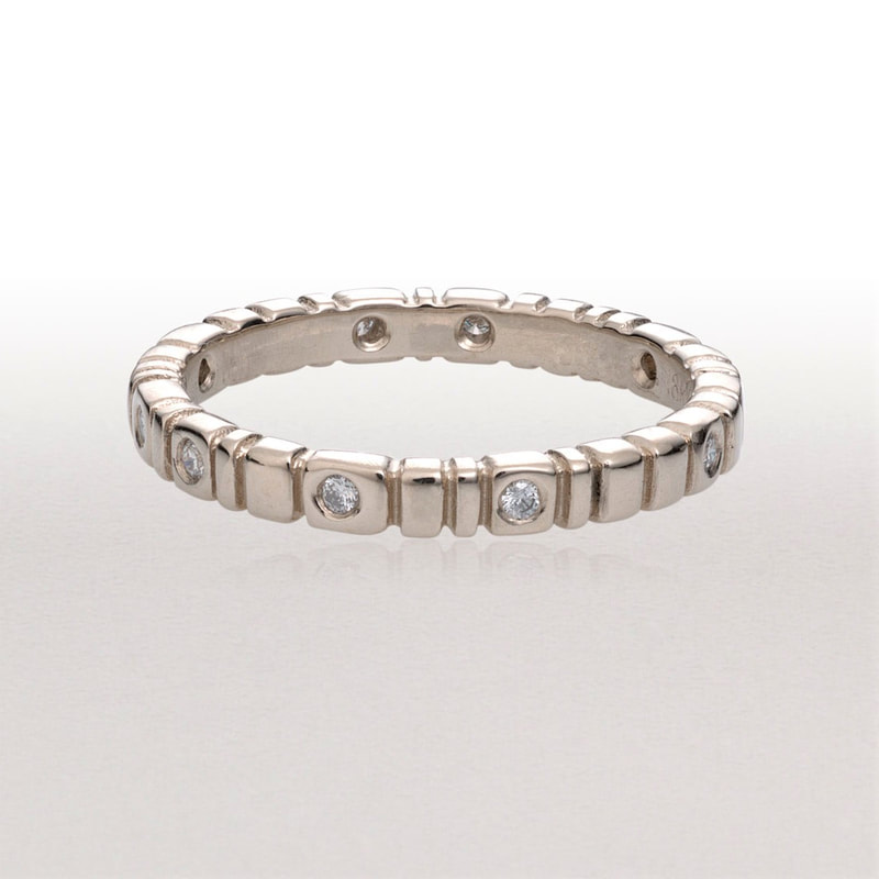 18 Karat White Gold thin band ring with notches and flush set diamonds all the way around.