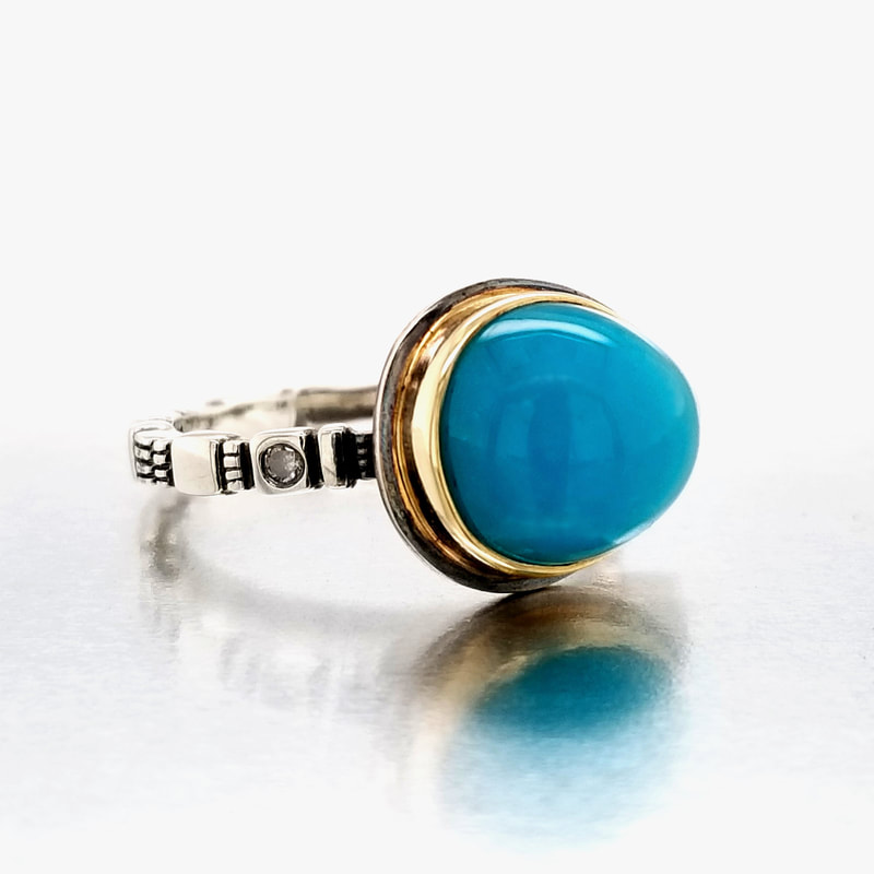 Platinum Silver ring with one cabochon Chrysocolla stone bezel set in 18KY and a diamond on each side on the band.