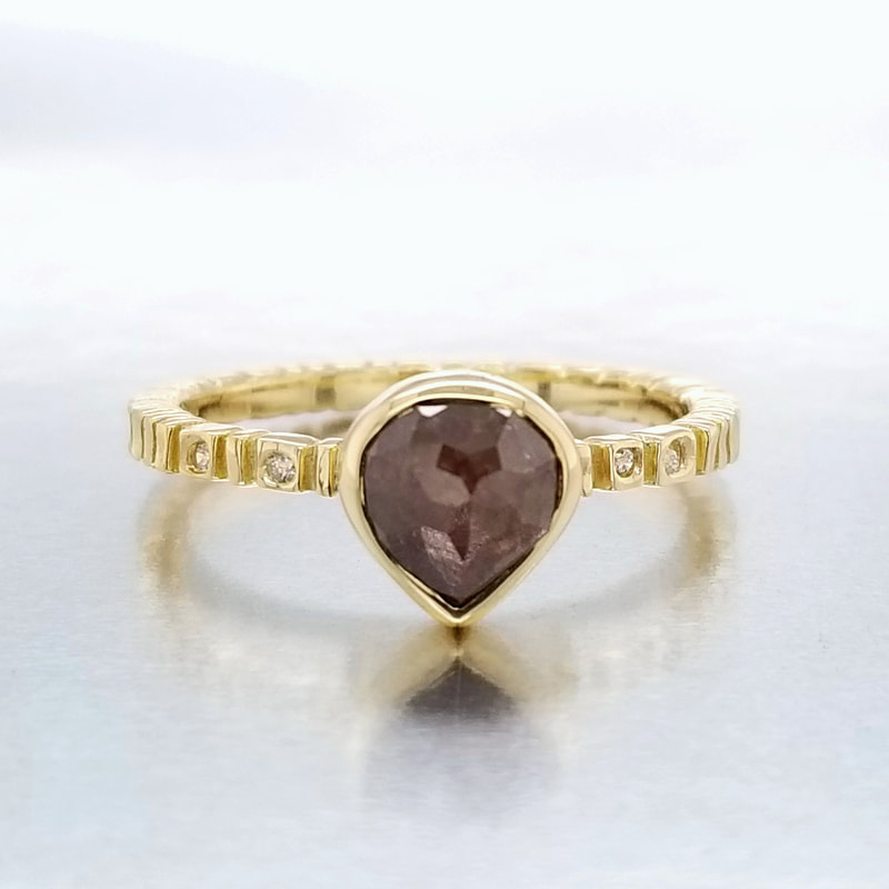 18 Karat Yellow Gold Ring with one Pear Shaped Natural Red Rustic Diamond in the center and flush set diamonds on the band.