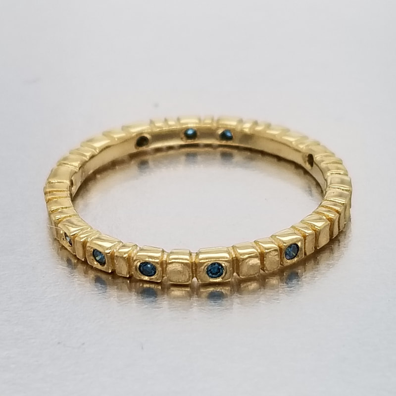18 Karat Yellow Gold thin band ring with Blue Diamonds all the way around.