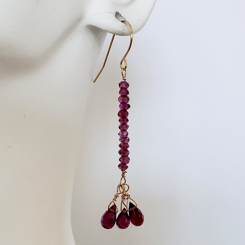 14 Karat Yellow Gold dangle earrings with a line of roundish Rhodolite Garnet beads and three pear shaped ones at the bottom.
