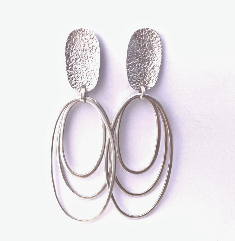 Silver oval textured post earrings with three hoops dangling from each.