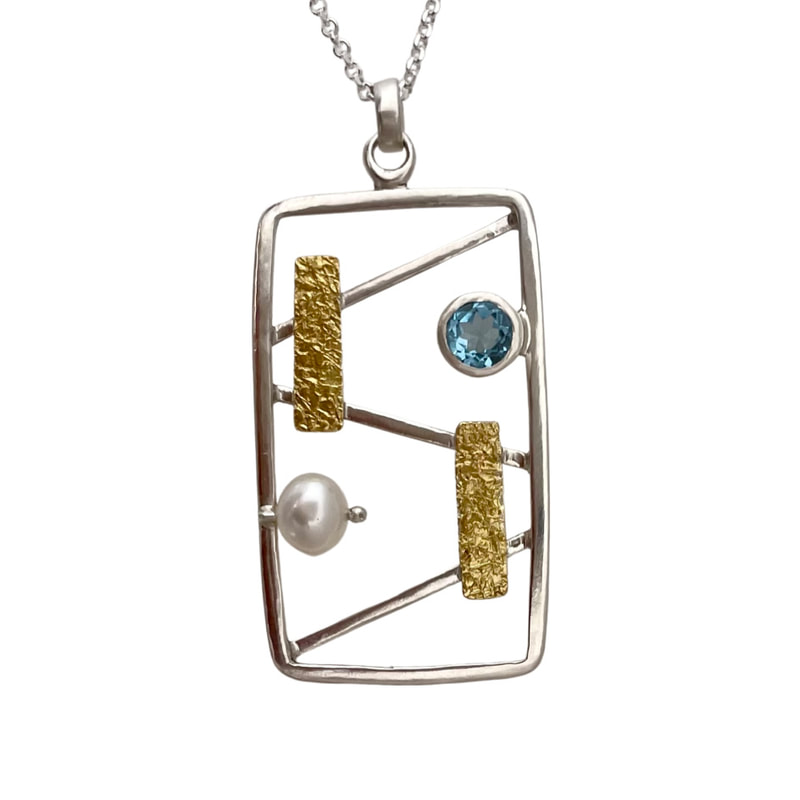 22 Karat Yellow Gold and Sterling Silver Bi-metal pendant with Blue Topaz and pear with a silver open frame on a chain.