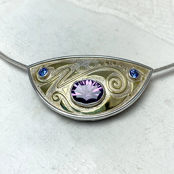  18 Karat Yellow Gold & Sterling Silver Pendant set with an Amethyst in the center and two Tanzanites on a 3mm Omega Collar.