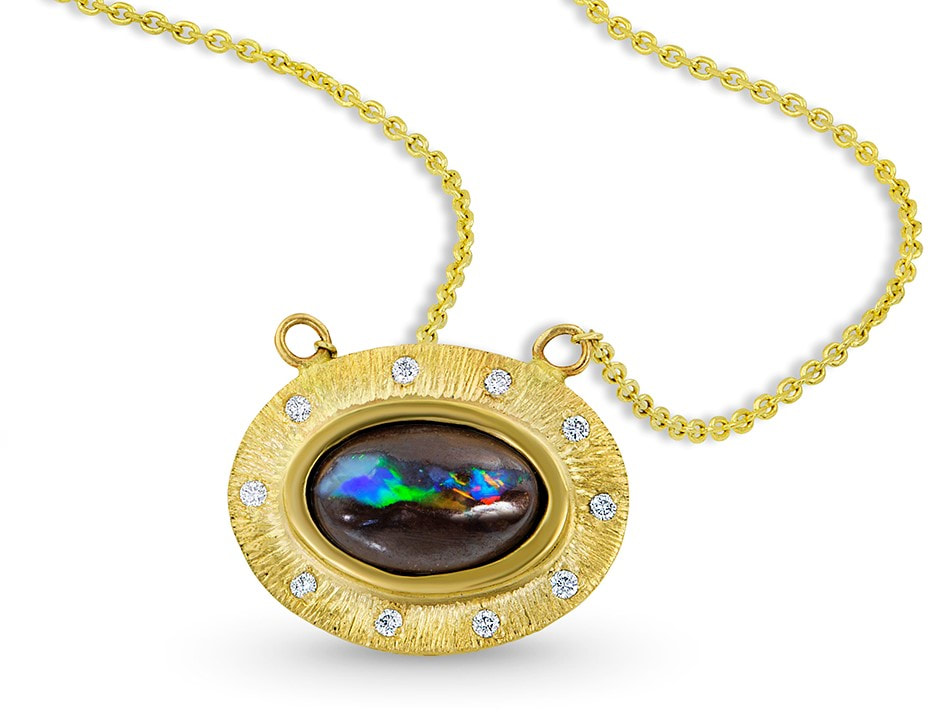 A gold pendant with a natural oval Black Opal with spaced inset diamonds around it.