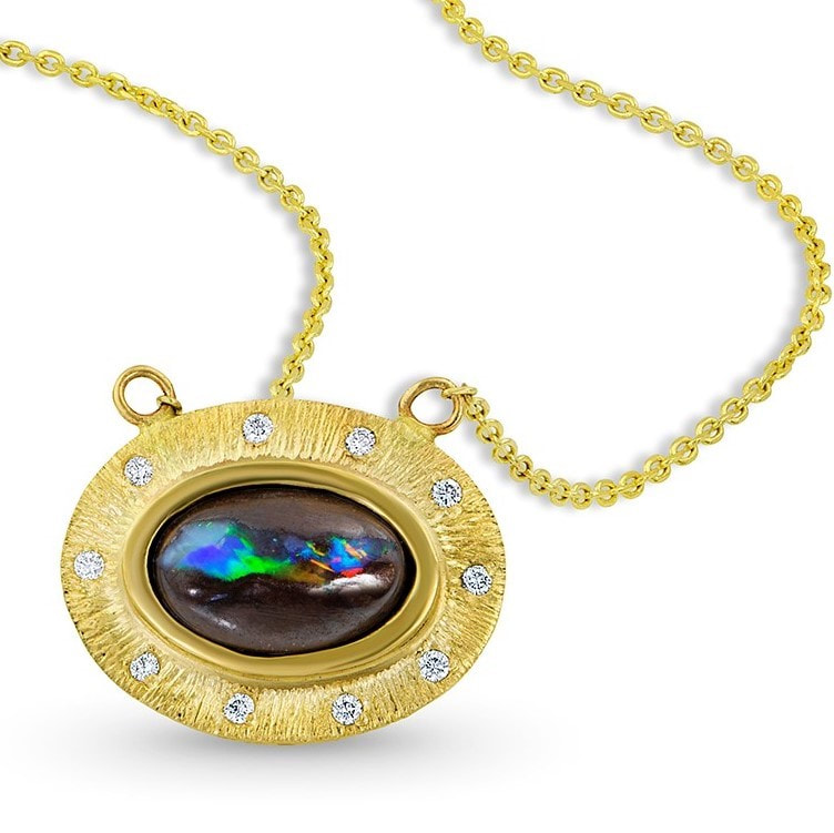 14 Karat Yellow Gold necklace with an oval opal in the center with a gold bezel and diamonds and an attached chain.