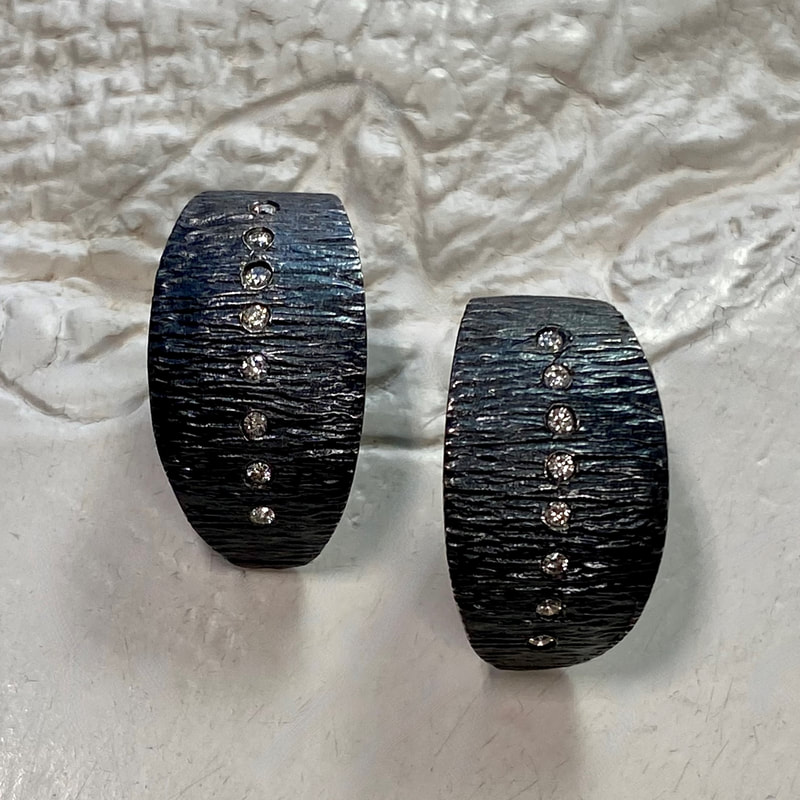 Oxidized textured post earrings with inset white diamonds down the center of each. 