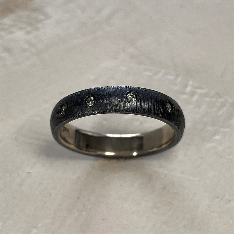 Oxidized Sterling Silver domed, textured band with spaced inset diamonds all the way around.