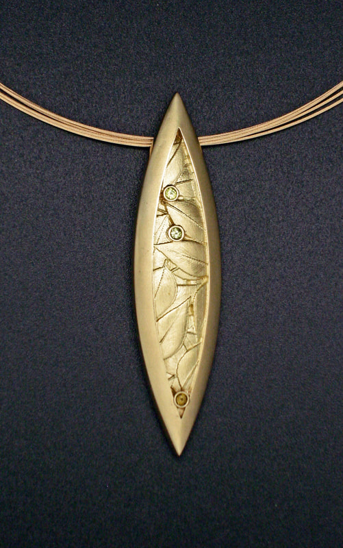 18 Karat Yellow Gold Marquise shaped pin/pendant with carved leaves and Chrystoberyl on a 5-Strand gold chain.
