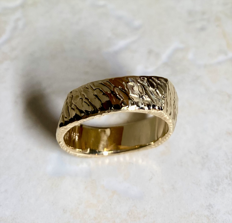 Yellow gold square slightly slanted band with carved texture.