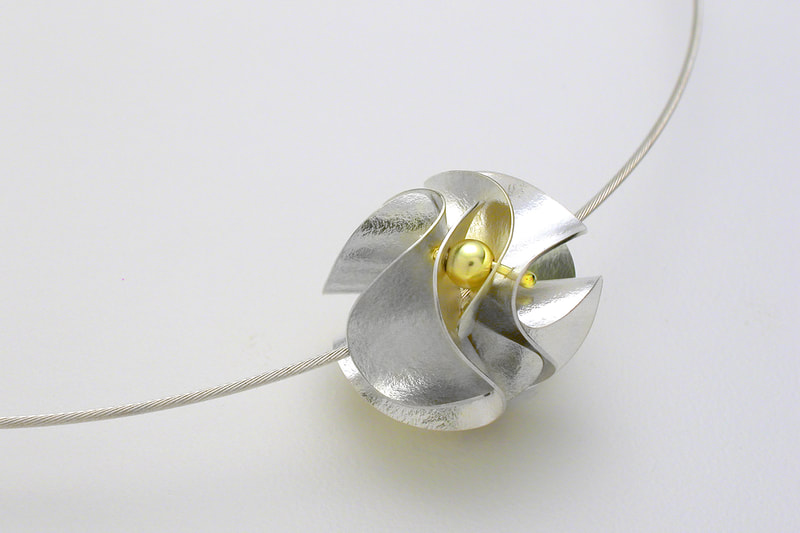 Sterling Silver round pendant with curved pieces in a round shape with an 18 Karat Yellow Gold round bead.