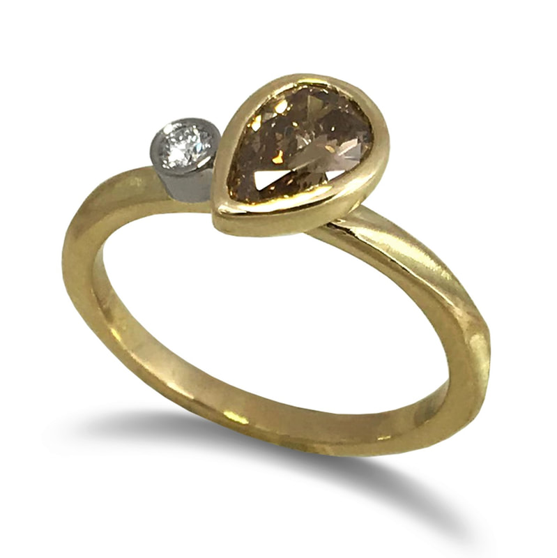 8K Yellow Gold & 18K Palladium White Gold with a pear shaped brown diamond on the top and a small round white diamond on the side.
