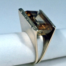 14 Karat Yellow Gold Ring with an emerald cut citrine with a split shank and a channel bar of gold holding each side of the Citrine.