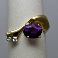 14 Karat Yellow Gold curved ring with an oval Amethyst and 2 smaller diamonds.
