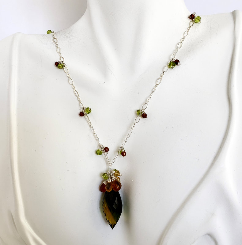 Silver necklace with dangling gemstones on the chain and a Bi-Color Quartz in the center with gemstones clustered above it.