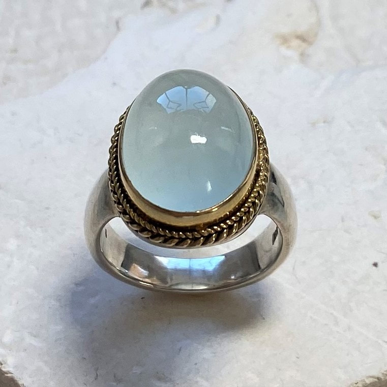 Sterling Silver ring with a Aquamarine in the center set in a bezel of 18 Karat Yellow Gold.