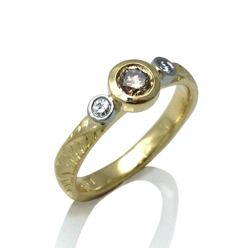 Gold ring with a natural brown diamond in the center flanked by one white diamond on each side.