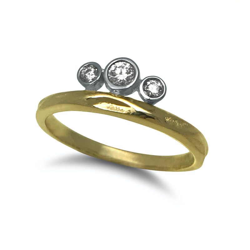 14 Karat Yellow gold thin band with white gold bezeled diamonds off the edge of the band.