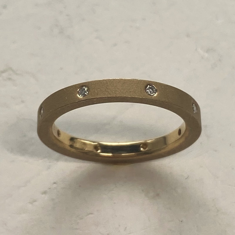 18 Karat Yellow Gold ring with spaced matte finish ring with flush-set diamonds all the way around.