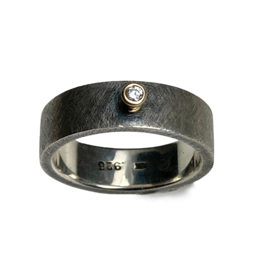 Oxidized Sterling silver flat band ring with one 18K Yellow Gold Bezel set Diamond in the center.