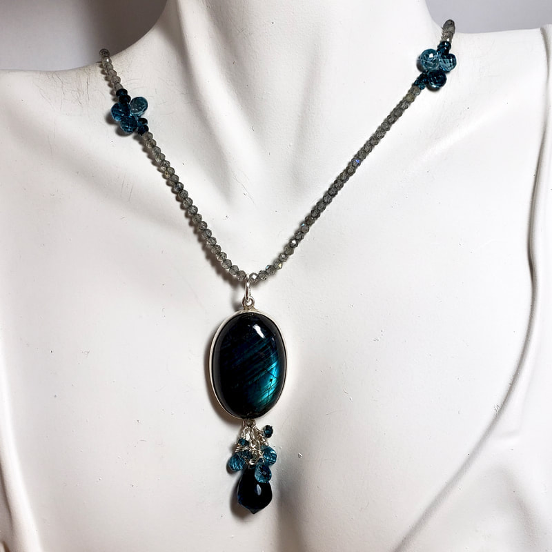Sterling Silver Necklace with a bezel set oval Labradorite in the center with dangles of Blue topaz and Blue Quartz on a Beaded chain of labradorite and Blue Topaz
