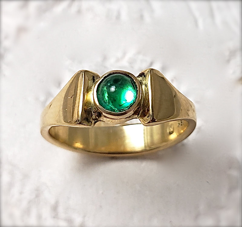 18 Karat Yellow Gold ring with a round Emerald in the center.