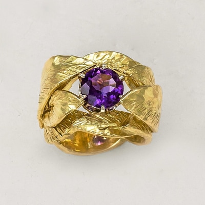18 Karat Yellow Gold Ring with carved leaves, 8mm wide and an Amethyst in the center.